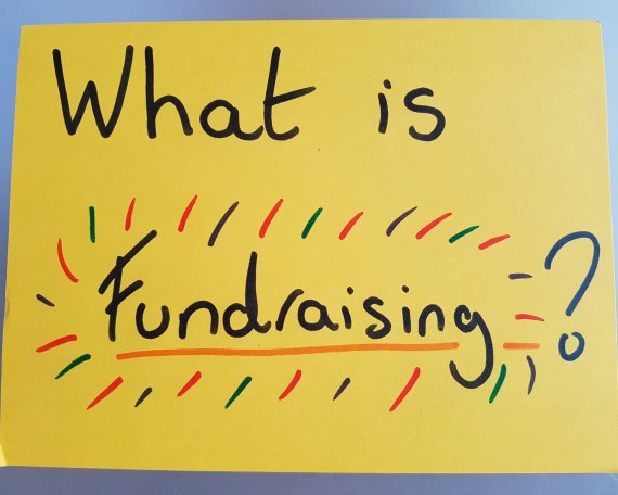 A giant yellow post-it note, saying "What is fundraising?" in large letters