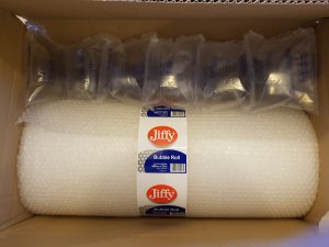 A large roll of bubble wrap is backed inside a cardboard box, protected by more bubble wrap