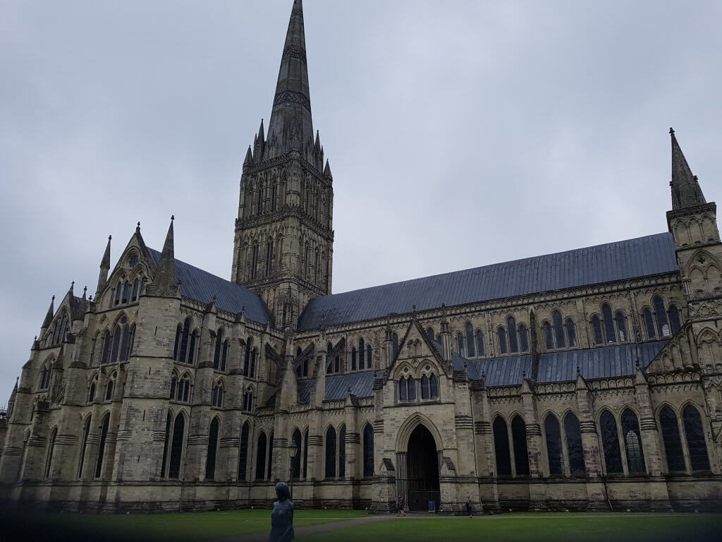 The outside of Salisbury Cathedral, showing the gigantic spire. The statue of a woman can be seen in front of the building