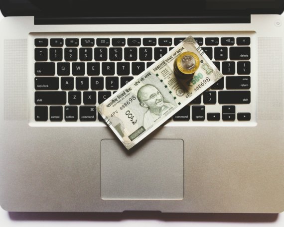 A laptop with money piled on the keyboard