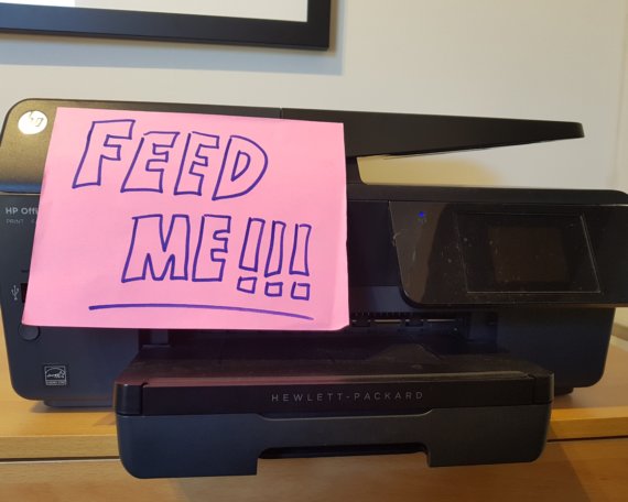 A printer with a sign on saying 'Feed Me'